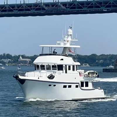 2011 Nordhavn 60 Trawler ONYXIA cruising under a bridge on a sunny day