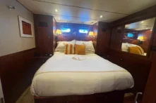 2025 Nordhavn 475 Listo master stateroom with island queen bed, twin portholes, and mirrored wardrobe
