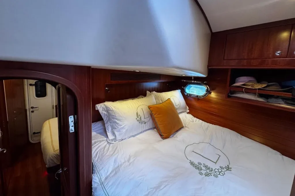 2025 Nordhavn 475 Listo guest stateroom with queen berth, mahogany paneling, and porthole natural light