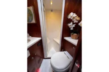 2025 Nordhavn 475 Listo guest head with separate glass shower stall, marine toilet, and built-in mahogany cabinetry