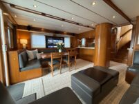 N6416 - AEGEAN MIST - salon wide-angle view from aft showing dining area, galley pass-through, gray leather settee, staircase, and warm teak joinery