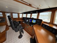 N6416 - AEGEAN MIST - pilothouse from forward showing two black leather helm seats, stainless wheel, Garmin chartplotter displays, and water views through surrounding windows