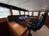 N6416 - AEGEAN MIST - pilothouse overview from starboard side showing full navigation console, helm wheel, three black pedestal captain's chairs, and surrounding water views