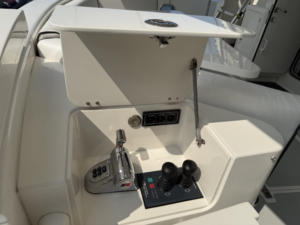 N6416 - AEGEAN MIST - close-up of cockpit helm station showing chrome throttle controls, joystick docking system, and start/stop/horn switches on white fiberglass console