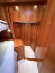 N6416 - AEGEAN MIST - forward stateroom detail showing overhead teak paneling and cabinetry with white berth linens and bedside storage, photographed from above
