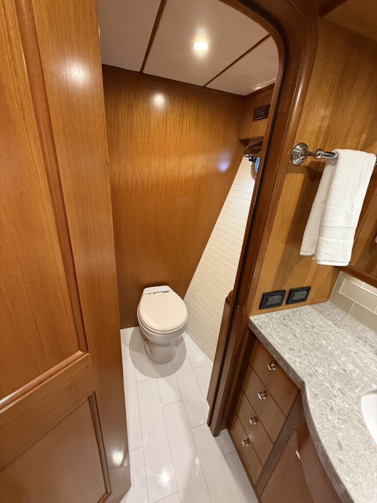 N6416 - AEGEAN MIST - overhead view of master head bathroom showing toilet, teak sole, granite countertop, white tile shower area, and cabinetry