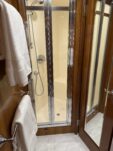 N6416 - AEGEAN MIST - master head glass shower enclosure with stainless trim, hand shower, and folded white towels on teak vanity ledge