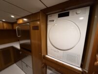 N6416 - AEGEAN MIST - Miele front-loading clothes dryer built into teak cabinetry in the yacht's laundry area