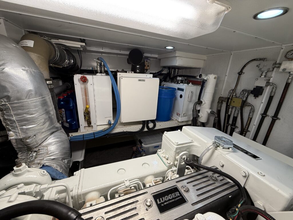 N6416 - AEGEAN MIST - engine room showing Lugger main engine with white and grey components, blue water maker filters, and organized plumbing on the bulkhead
