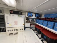 N6416 - AEGEAN MIST - electrical compartment with white distribution panel labeled NO:1 2231 98, Victron charge controller, battery bank on shelving, and storage tubs
