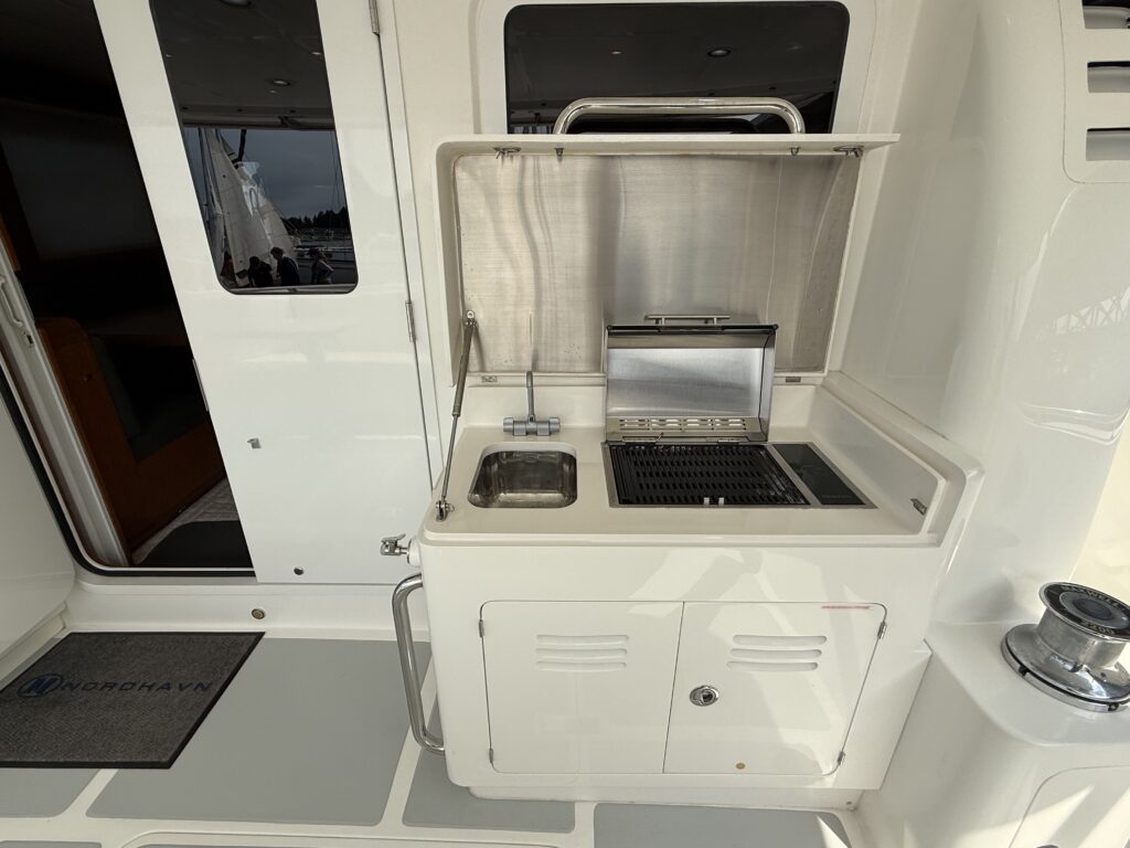 N6416 - AEGEAN MIST - cockpit outdoor galley station with lid open revealing stainless sink, grill, and preparation surface built into white fiberglass cabinetry