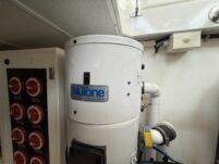 N6416 - AEGEAN MIST - engine room showing NuTone central vacuum system canister unit alongside red rotary battery switches on a panel