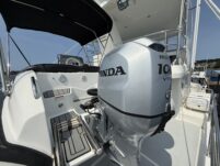 N6416 - AEGEAN MIST - Walker Bay tender with Honda 100 VTEC four-stroke outboard motor mounted on davits beside the yacht, with marina and blue sky in background