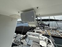 N6416 - AEGEAN MIST - exterior speaker mounted on underside of flybridge overhang with marina dock, sailboats, and tender on deck visible below