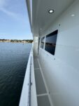 N6416 - AEGEAN MIST - low-angle view along the side deck looking toward the bow showing an overhead skylight hatch, calm blue water, and distant shoreline