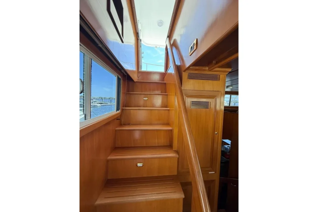 2006 Nordhavn 64 - KARIWA 24 - Wooden staircase inside a yacht with windows and blue sky.