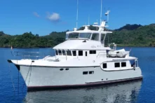 2006 Nordhavn 64 - KARIWA 4 - 2006 Nordhavn 64 yacht on serene water with lush green hills in the background.