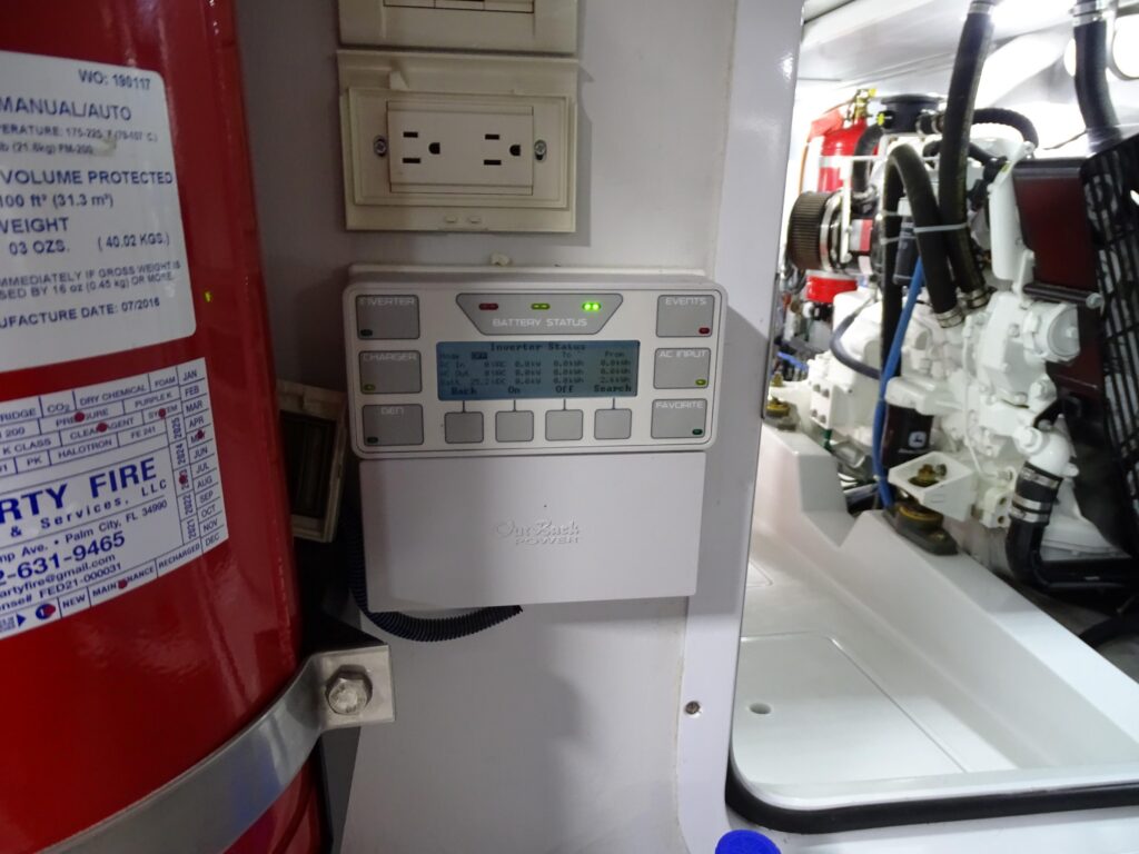 2017 Nordhavn 60 - REDEEMED 49 - An engine room with a fire extinguisher, control panel, and engine in the background.