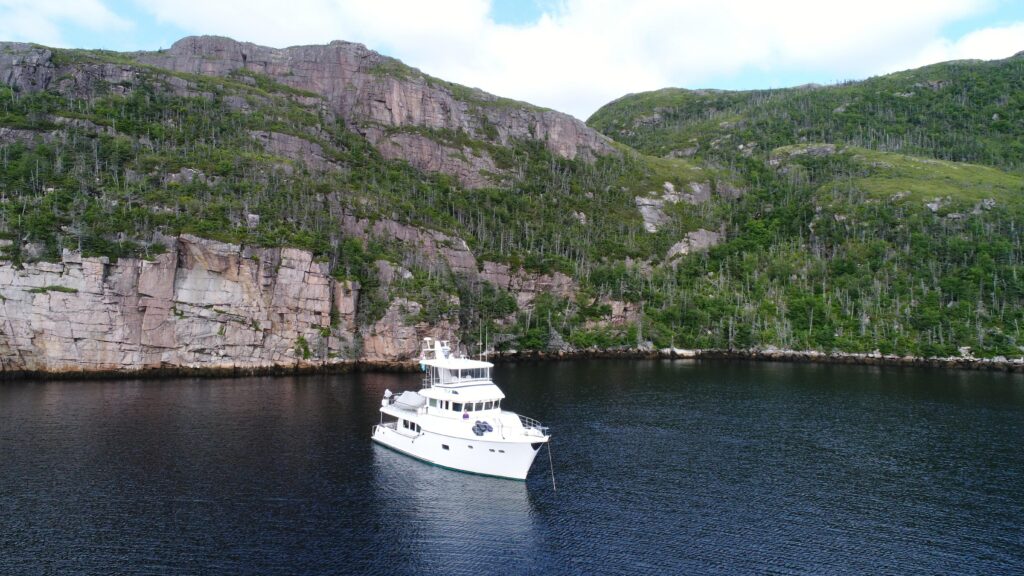 2017 Nordhavn 60 - REDEEMED 2 - A 2017 Nordhavn 60 yacht anchored near a rocky coastline.