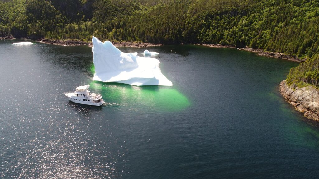 2017 Nordhavn 60 - REDEEMED 3 - A 2017 Nordhavn 60 sails past a large iceberg in a calm bay.